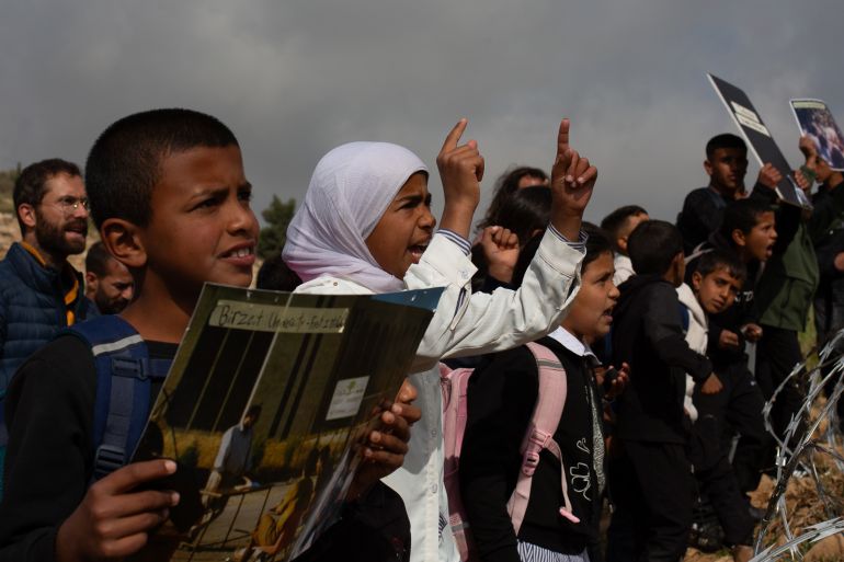 Children march to school blocked by settler fence in West Bank.